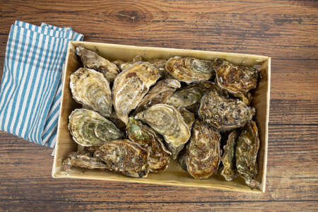 top view of fresh oysters in a hamper on a wooden table