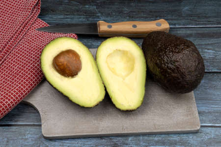cut and whole avocados on a gray background