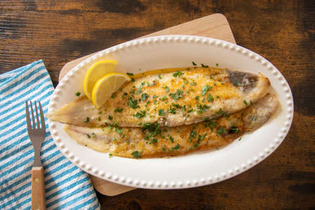 baked fish with lemon and herbs in dishの写真素材