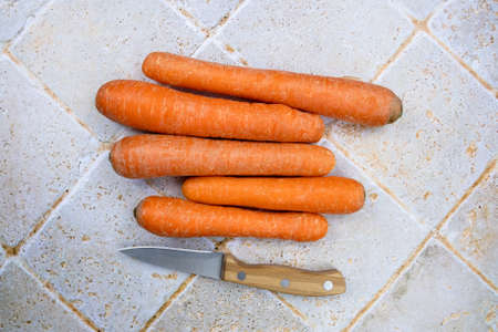 top view of several raw carrots isolated on a table with a knifeの写真素材