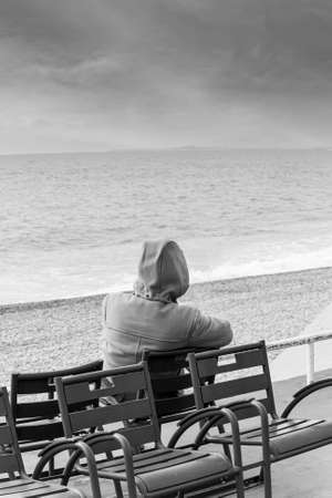 man sitting on the bench and looking at sea