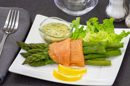 delicious salmon with asparagus and sauce on white plateの写真素材