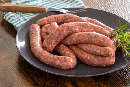 raw sausages for grilling in a plate on a tableの写真素材
