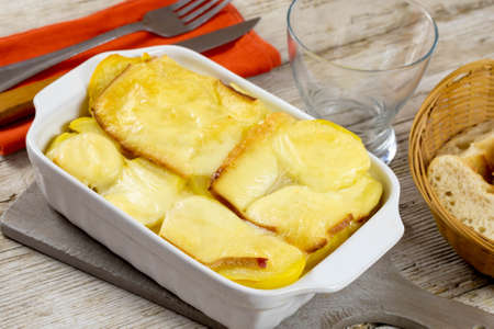 potato with raclette cheese on wooden tableの写真素材