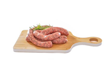 raw herb sausages on a wooden board on a white backgroundの写真素材