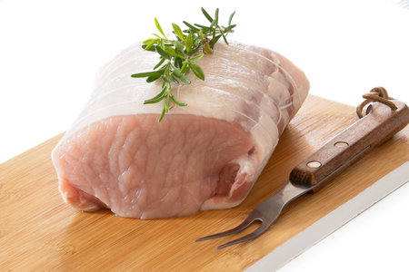 raw pork roast on a board on a wooden backgroundの写真素材