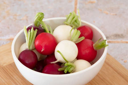 close up of tricolor radishes in a bowl on a tableの写真素材