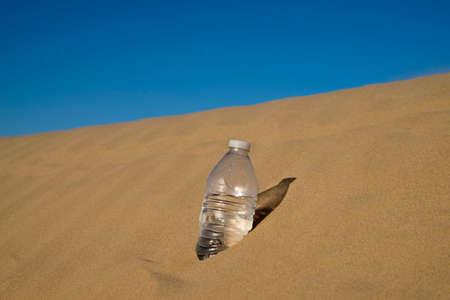 Bottle of Water Standing up in the Desert Sandの写真素材