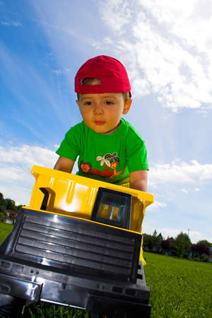 child playing with truck outside over deep blue sky