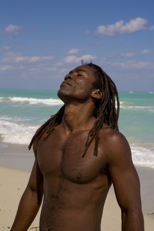 black man tilting his head behind on the beach over blue sea and blue skyの写真素材
