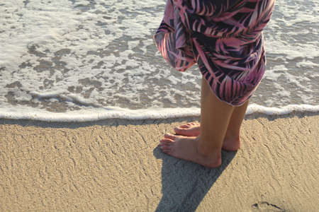 Beach travel - woman walking on sand beach. Closeup detail of female feet and golden sand on beachの写真素材