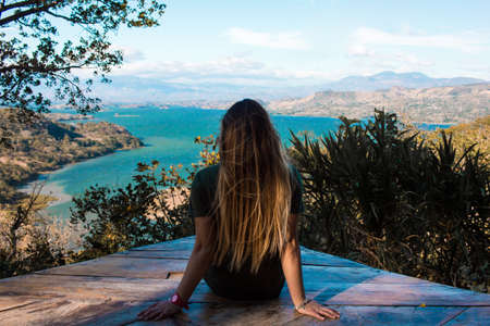 Young woman watching the beautiful landscape of the lake between mountainsの写真素材