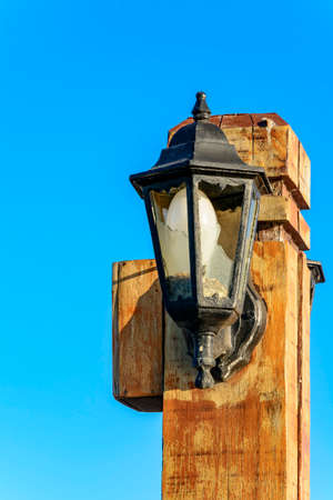 Wooden light pole with broken glass on the pier from Armao Beach in Buzios
