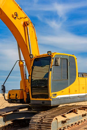 Excavator cabin and gears on the beach with blue sky and sea in the backgroundの写真素材