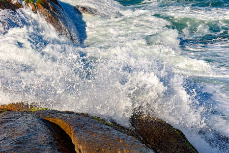 Sea water spray over the stones on the beachの写真素材