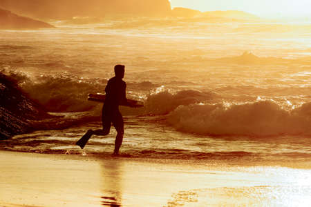 Bodyboarder going into the water at Ipanema tropical sunrise in Rio de Janeiroの写真素材