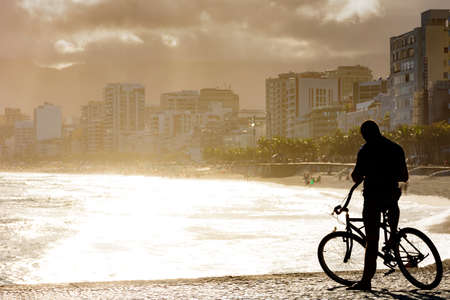 Cyclist in front of the sea during late afternoon at Arpoador beach in Ipanema, Rio de Janeiro