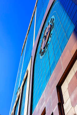 Commercial and business building facade with clock and blue sky in the backgroundの写真素材