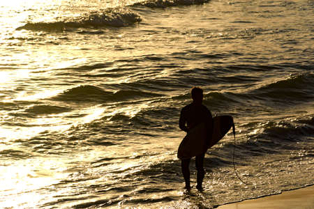Surfer walking on the water at tropical sunset