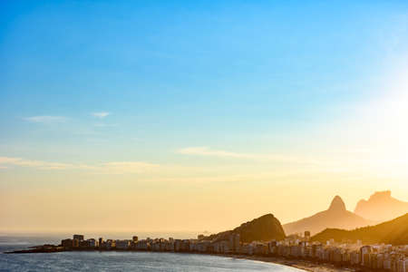 Copacabana beach in Rio de Janeiro during sunset with its buildings and the mountains in the backgroundの写真素材