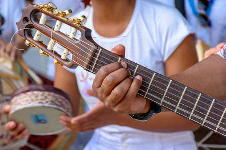 Detail of guitarist's hands and his acoustic guitar at an outdoor samba presentationの写真素材