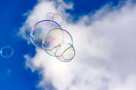 Soap bubbles with their colors and transparencies floating in the blue skyの写真素材