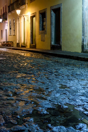 Streets of the Pelourinho district with its facade of colonial houses and cobblestones wet by rain illuminated at nightの写真素材