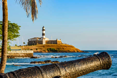 Old cannon and the Barra Lighthouse (Lighthouse of Barra) one of the main historical buildings and...