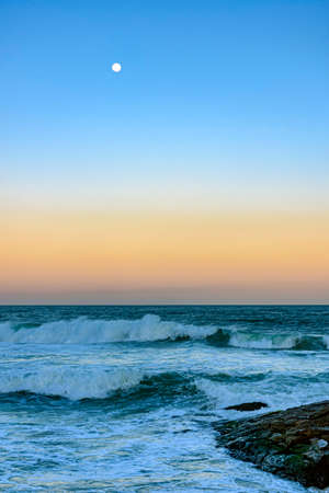 Moon over the sea and waves during sunset at Ipanema beach in Rio de Janeiro, Brazil