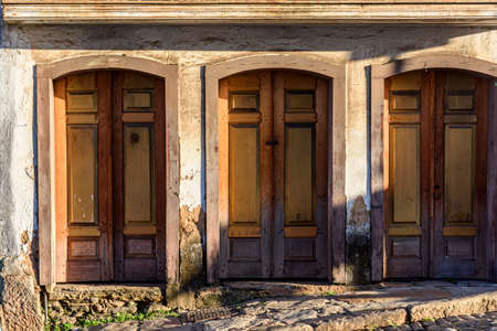 Old wooden doors spoiled by time on the facade of a colonial style house in the city of Ouro Preto,...