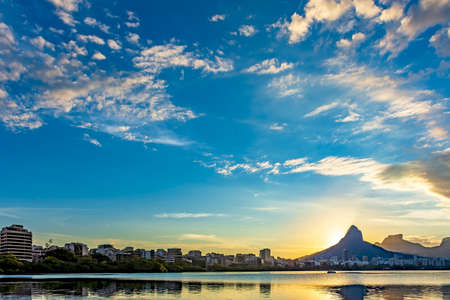 Sunset at Rodrigo de Freitas lagoon with the buildings and hills of the city of Rio de Janeiro...