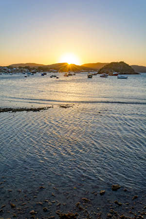 Sunset behind the hills and reflected in the sea waters of the city of Buzios on the north coast of Rio de Janeiroの写真素材