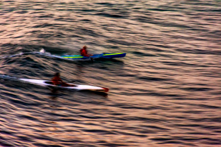 Canoeing at sunset in the sea of the city of Salvador in Bahia with blurred motion and unrecognizable peopleの写真素材
