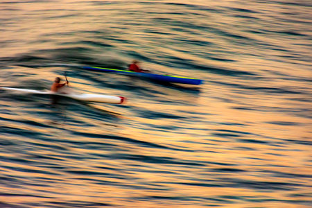 Canoeing on the wave at sunset in the sea of the city of Salvador in Bahia with blurred motion and unrecognizable peopleの写真素材