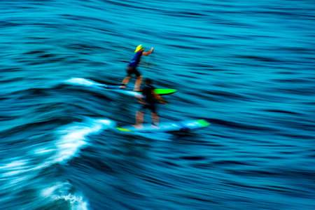 Stand up paddle on the waves at sunset in the sea of the city of Salvador in Bahia with blurred motion and unrecognizable peopleの写真素材