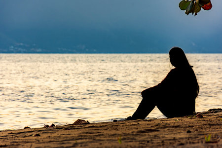 Girl sitting in front of the sea during sunset in Ilhabela on the north coast of SÃ£o Pauloの写真素材