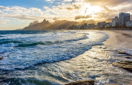 Sunset on Ipanema beach in Rio de Janeiro with its buildings in front and mountains in the backgroundの写真素材