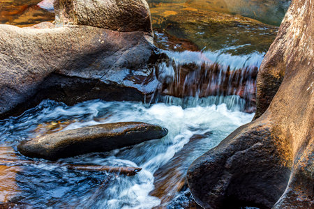 Small river and waterfall with water flowing between the rocksの写真素材