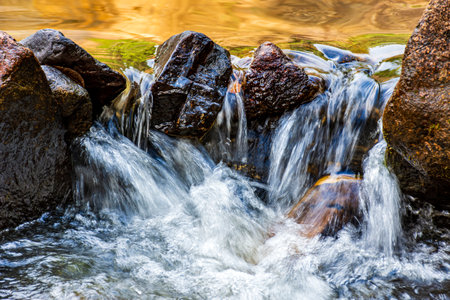 Water flowing between rocks in a small streamの写真素材
