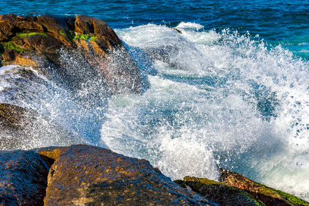 Sea water splashing and foam after wave crashes against the rockの写真素材