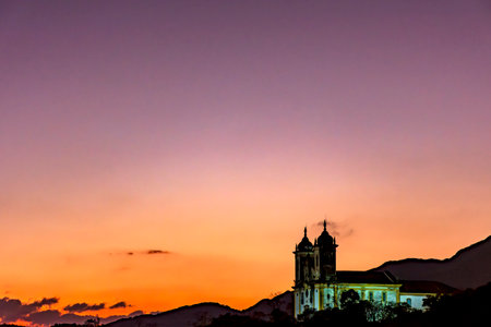 Tower of an old baroque church and mountains in the city of Ouro Preto in Minas Gerais during sunsetの写真素材