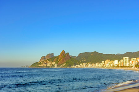 Ipanema Beach in the city of Rio de Janeiro at sunrise with the sea, buildings and mountainsの写真素材