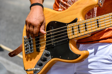 Hands playing an electric bass guitar on the street in a sunny dayの写真素材