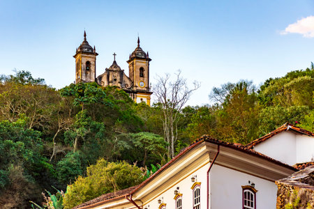 Historic buildings and a baroque church amidst the vegetation of the hills of the city of Ouro Pretoの写真素材