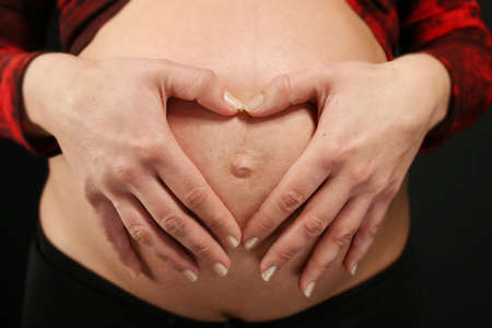 Hands making a heart on the belly of a pregnant womanの写真素材