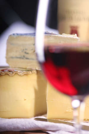 Tomme de Savoie, a semi firm french cheese, Cambazola, a creamy german cheese and a glass of wineの写真素材