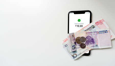 Chinese Yuan Money banknotes and top up smartphone on a white background for using online digital money to pay with QR code scanning, China. Add textの写真素材