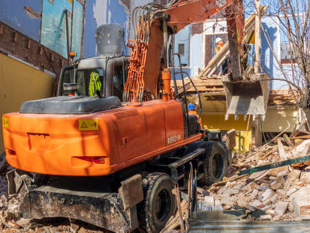 Demolishing an old house with a large excavator in this image of a street in Barcelona, Spain.のeditorial素材