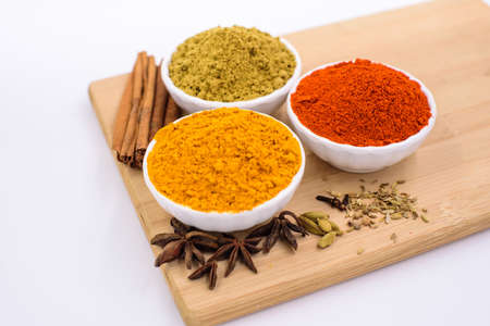 Herbs and spices such as star anise, cinnamon, turmeric, chilli powders and other on a chopping boardの写真素材