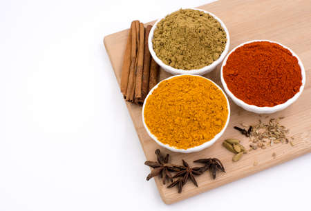 Herbs and spices such as star anise, cinnamon, turmeric, chilli powders and other on a chopping boardの写真素材